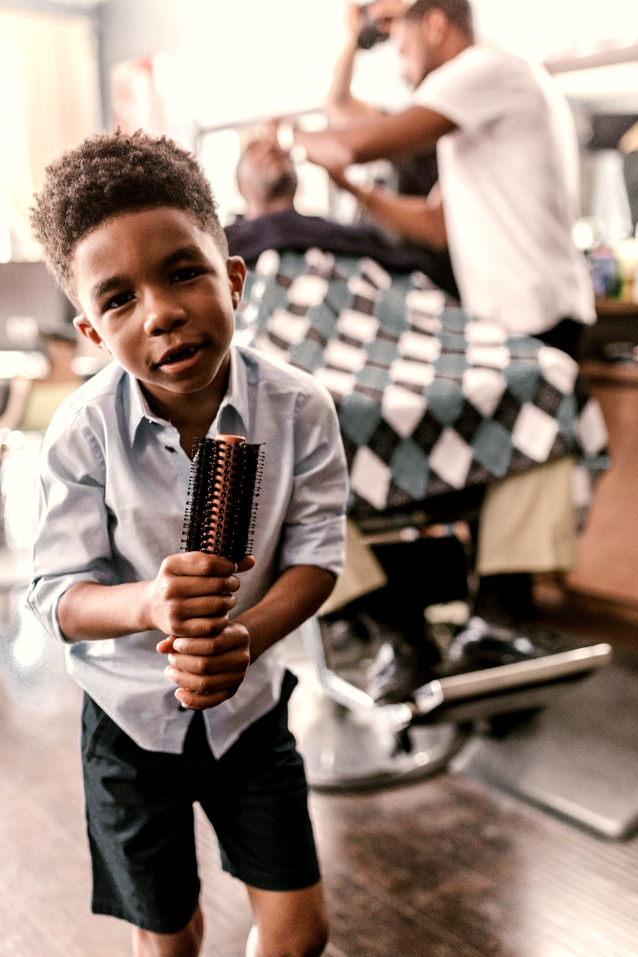 Young boy holding a brush at a barbershop
