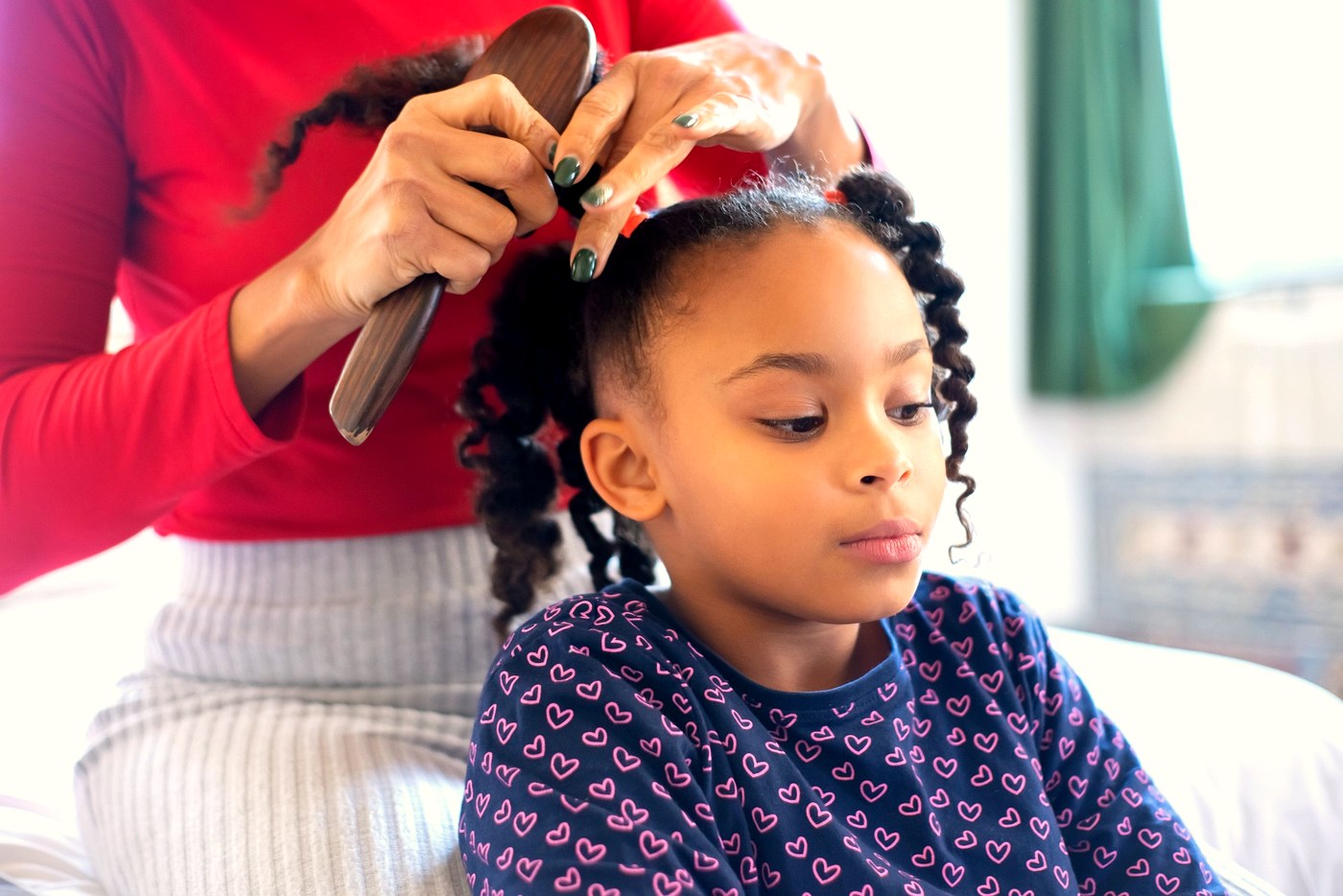 Caregiver styling a child's hair at home